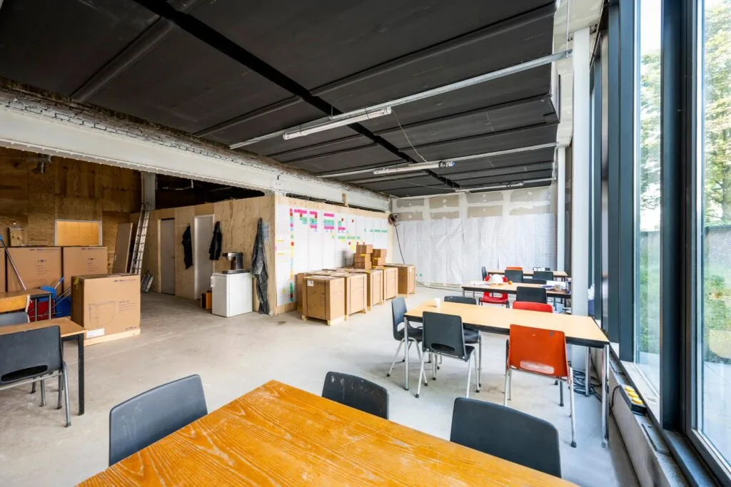 Ruimte in een bedrijfs- of creatief pand aan de Karel du Jardinstraat met werktafels, kartonnen dozen en een wand vol post-its.